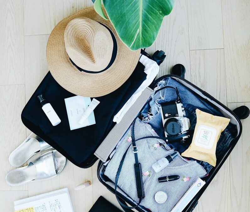 open suitcase with travel essentials and hat